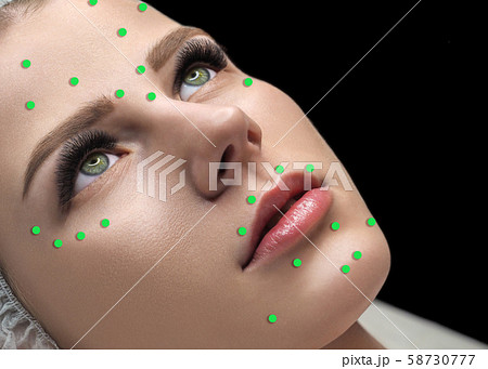 Female face marked with green dots on the main facial spots for beauty injections. Caucasian woman Female face marked with green dots on the main facial spots for beauty injections. Caucasian woman 58730777