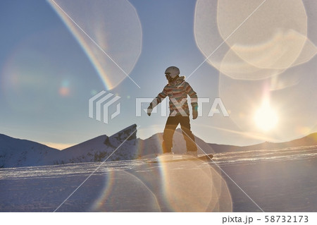 Snowboarder in sun flare, water drops on lens Snowboarder in sun flare, water drops on lens 58732173