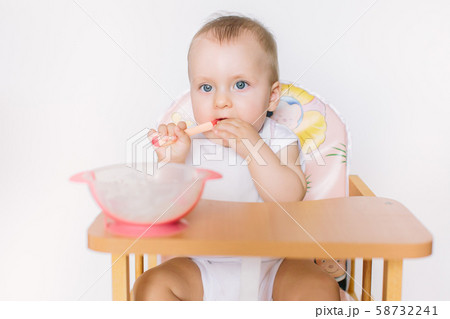 portrait of happy young baby girl sitting on high chair and feed her self 58732241
