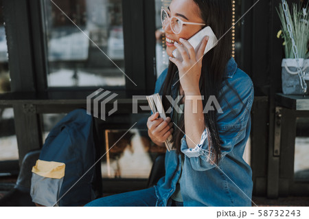 Happy Asian lady in glasses holding smartphone Happy Asian lady in glasses holding smartphone 58732243