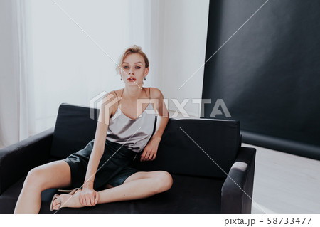 Portrait of a beautiful fashionable woman sits on a black office sofa Portrait of a beautiful fashionable woman sits on a black office sofa 58733477