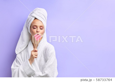 Young woman in towel and bathrobe with lollipop isolated over purple background Young woman in towel and bathrobe with lollipop isolated over purple background 58733764