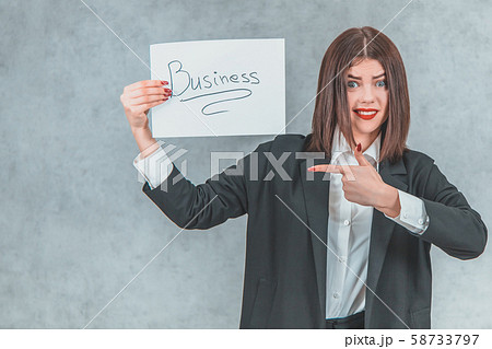 Inspired businesswoman in black suit showing sheet of paper with word business , pointing her finger Inspired businesswoman in black suit showing sheet of paper with word business , pointing her finger 58733797