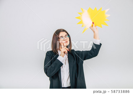 Portrait of an excited young business woman raising up empty sparkle-like speech bubble, looking at 58733886