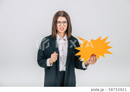 Excited young business woman holding an empty sparkle-like speech bubble, clenching her fists 58733921