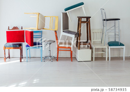 lots of different chairs in the interior of an empty white room 58734935