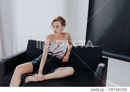 Beautiful fashion business blonde woman on a black sofa in the office Beautiful fashion business blonde woman on a black sofa in the office 58736169