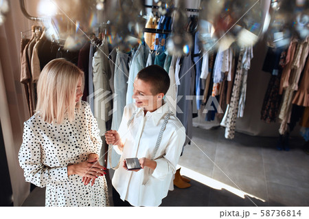 Caucasian tailor discuss clothes sketch with interested beautiful client Caucasian tailor discuss clothes sketch with interested beautiful client 58736814