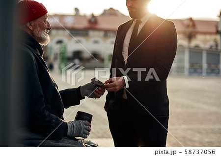 Businessman give money donation to pity beggar Businessman give money donation to pity beggar 58737056