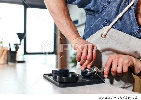 Hands of barista tamping ground coffee 58739732