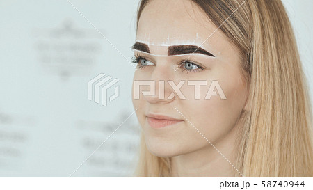 Create permanent eyebrow makeup. Marking the shape of the eyebrows. 58740944