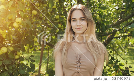 Portrait of a young beautiful seventeen-year-old blonde girl in the apple orchard. Portrait of a young beautiful seventeen-year-old blonde girl in the apple orchard. 58740975