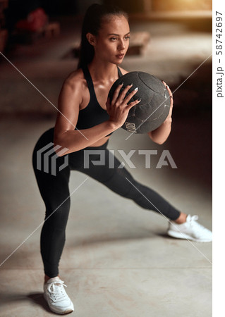 sporty young woman practicing sqauts with ball in gym sporty young woman practicing sqauts with ball in gym 58742697