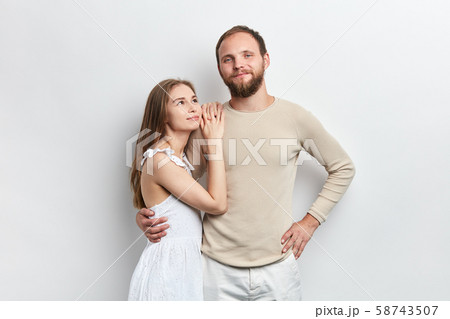 confident man with a hand on his hip hugging his woman 58743507
