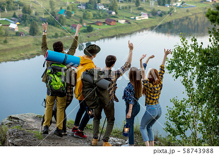 Young ambitious people with backpacks standing with raised hands Young ambitious people with backpacks standing with raised hands 58743988
