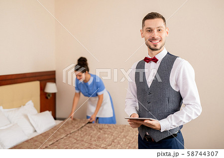 Successful hotel staff standing in front of camera on background of chamber maid 58744307