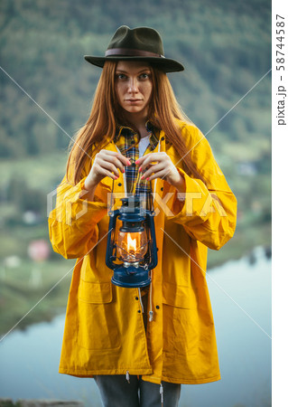 young scaared emotional attractive girl in raincoat and hat holding lantern young scaared emotional attractive girl in raincoat and hat holding lantern 58744587