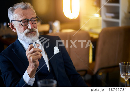 Senior man holding electronic cigarette sitting in rich restaurant. IQOS, modern technologies, stop 58745784