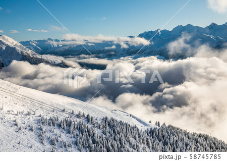 Misty sunrise in the winter forest in the mountains. Alps, Switzerland. 58745785