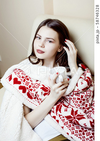young pretty brunette woman in her bedroom sitting in christmas decorated blanket, happy smiling 58746328