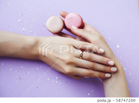 woman hands with manicure holding macaroons girl stuff on lilac background, cosmetic lifestyle 58747200