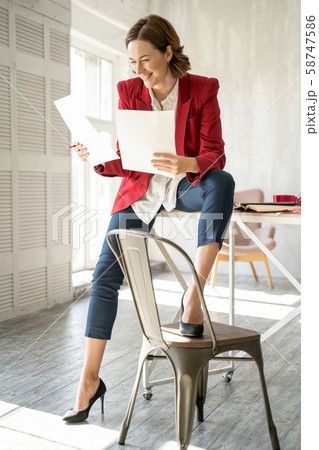 Happy fashion designer looking at her sketches Happy fashion designer looking at her sketches 58747586