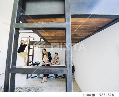 Mother reading story to children on bunk bed 58748281