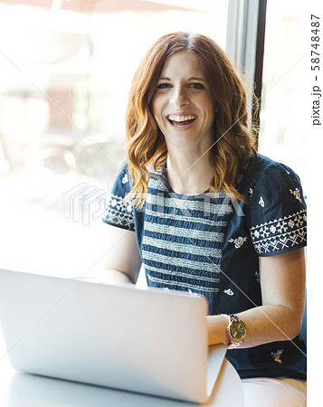 Smiling woman using laptop in cafe Smiling woman using laptop in cafe 58748487