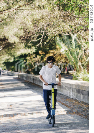 Young man using electric scooter on pavement 58748614