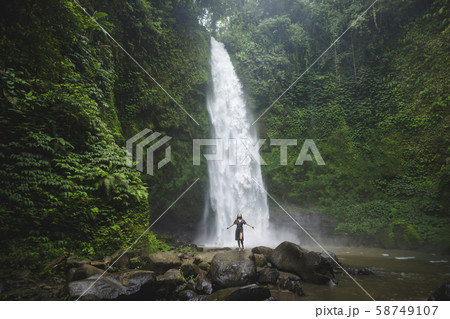 Woman standing by waterfall in Bali, Indonesia 58749107