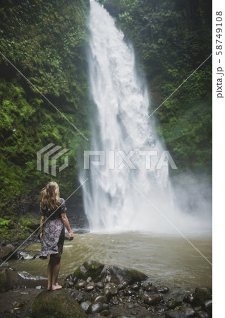 Woman standing by waterfall in Bali, Indonesia Woman standing by waterfall in Bali, Indonesia 58749108
