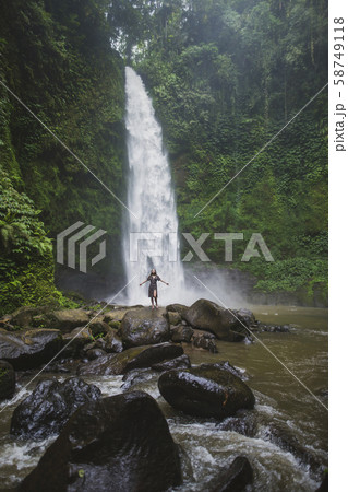 Woman standing by waterfall in Bali, Indonesia 58749118