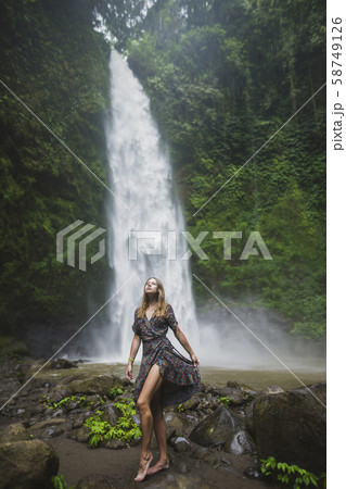 Woman standing by waterfall in Bali, Indonesia 58749126
