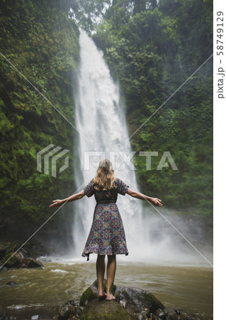 Woman standing by waterfall in Bali, Indonesia 58749129