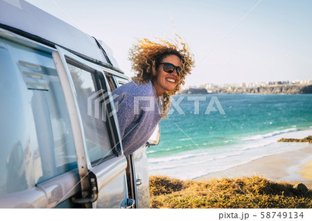 Smiling woman leaning out of camper van by beach in Fuerteventura, Canary Islands 58749134