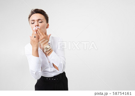 The young beautiful girl with short dark hair, a make-up in a white shirt, black trousers, with the 58754161