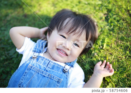 公園で寝転んで遊ぶ2歳の男の子の写真素材