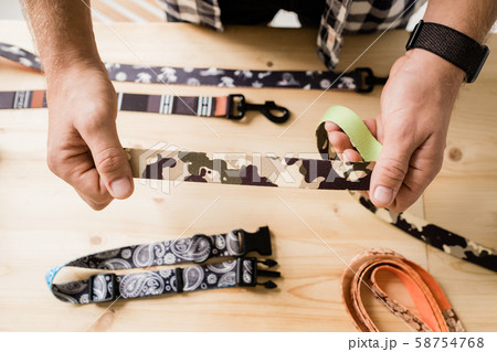 Overview of hands of craftsman holding one of creative pet collar workpieces Overview of hands of craftsman holding one of creative pet collar workpieces 58754768