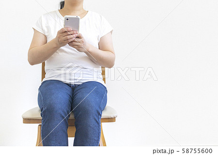 椅子に座ってスマートフォンを操作している少し太った女性 椅子に座ってスマートフォンを操作している少し太った女性 58755600