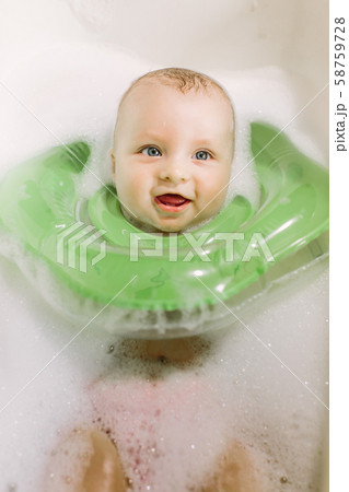 The baby is newborn, the girl is bathing in the bathroom with a inflatable circle around her neck. 58759728