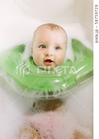 The baby is newborn, the girl is bathing in the bathroom with a inflatable circle around her neck. 58759729