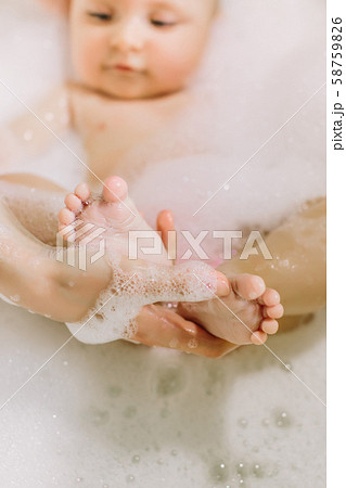 Happy laughing baby taking a bath playing with foam bubbles. Little child in a bathtub. Infant Happy laughing baby taking a bath playing with foam bubbles. Little child in a bathtub. Infant 58759826