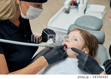 Little girl lying on dental chair with opened mouth Little girl lying on dental chair with opened mouth 58760482