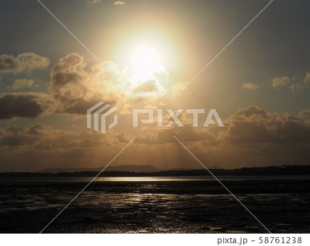 沈みゆく太陽の回りの虹のような輪と天使の梯子の写真素材