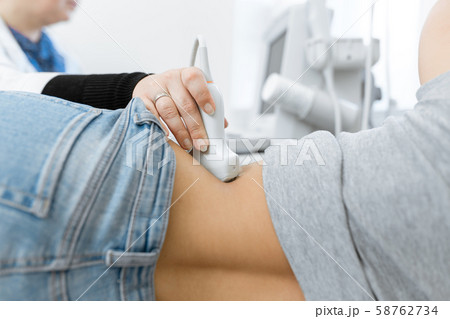 Close-up doctor conducts ultrasound diagnostics of 58762734