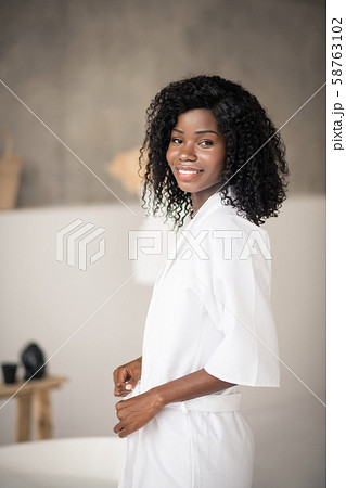 Dark-eyed woman wearing white bathrobe standing in the bathrobe Dark-eyed woman wearing white bathrobe standing in the bathrobe 58763102