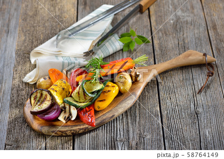 Vegan cuisine: Mixed grilled vegetables on a wooden cutting board Vegan cuisine: Mixed grilled vegetables on a wooden cutting board 58764149