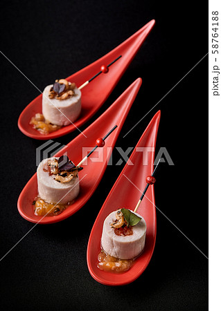 Goose liver pate, foie gras, served on black stone in Japanese red spoons. Paste served with jam and 58764188