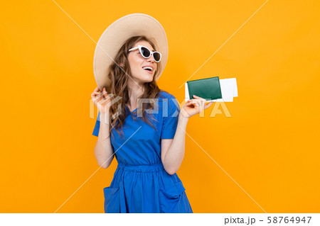 portrait of a girl on an orange background with a passport and plane tickets 58764947