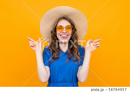 portrait of a girl with crossed fingers, a brunette makes a wish on a yellow background 58764957